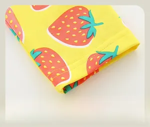 Détail de legging jaune pour enfant avec imprimés fraises rouges et finitions nettes