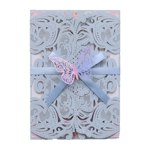 Intricate laser-cut blue wedding invitation card with ribbon and butterfly decor