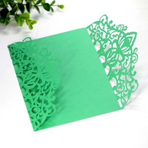 Macro shot of green laser-cut vine patterns on a textured wedding invitation cover