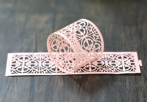 Macro detail of laser-cut pink paper napkin ring with vintage hollowed-out patterns