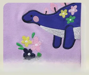 Détail de la broderie dinosaure et fleurs colorées sur tissu en maille violette