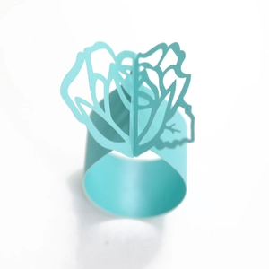 Detail of laser cut light blue paper napkin ring with a 3D rose flower design