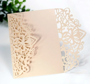 Close-up of laser cut champagne floral invitation pocket with elegant intricate patterns