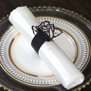 Detail of laser-cut black rose paper napkin ring on an elegant white napkin