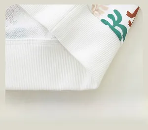Détail de l'ourlet côtelé avec coutures soignées sur sweat blanc pour garçon avec motif