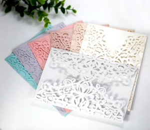 Detailed laser-cut floral lace textures on elegant pastel wedding invitation envelopes