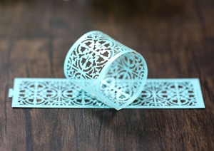 Macro view of light blue laser-cut decorative paper napkin rings with floral patterns