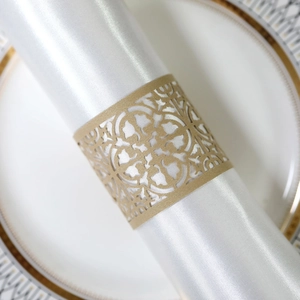 Detail eines lasertgeschnittenen goldenen Serviettenrings mit Blumenmuster auf Satin