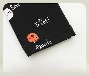 Close-up of girls leggings with Halloween pumpkin and ghost prints on black cotton fabric