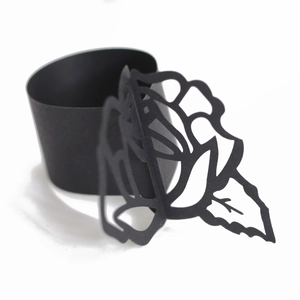Detail of laser-cut black paper napkin ring featuring a delicate hollow rose flower design