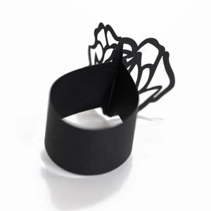 Detailed view of a black laser-cut paper napkin ring with floral hollow design