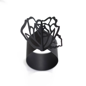 Detail of laser-cut black rose napkin ring featuring intricate hollow petal patterns
