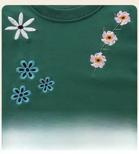 Detailed close-up of colorful 3D floral embroidery on a dark green kids' sweatshirt neck