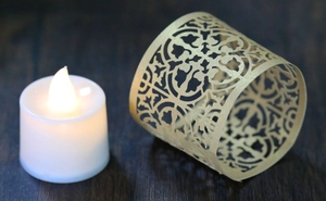 Detail of vintage hollow pattern golden lampshade with LED candle on wood surface