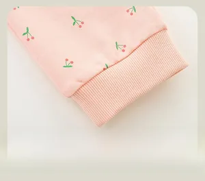 Detail of girls pink jogger pants featuring red cherry prints and elastic ribbed cuffs