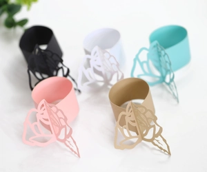Detail of laser-cut paper napkin rings with hollow rose patterns for wedding decor
