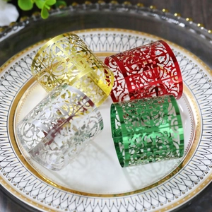 Close-up of four colorful laser-cut hollow napkin rings on a premium gold-rimmed ceramic plate