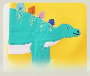 Macro view of bright yellow kids sweatshirt featuring a colorful dinosaur embroidery
