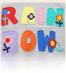 Detailed close-up of rainbow appliqué and floral embroidery on gray cotton kid's sweatshirt