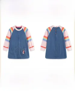 Detail of girls denim dress featuring penguin embroidery and colorful striped sleeves