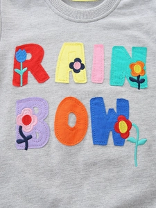 Girls' grey sweatshirt featuring colorful RAINBOW letter patches and floral embroidery