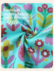 Détail du tissu 100% coton avec imprimés floraux colorés sur une robe bleu clair pour fille