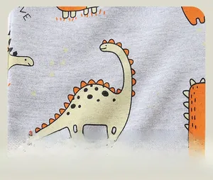 Close-up of grey jogger fabric featuring colorful cartoon dinosaur prints and text