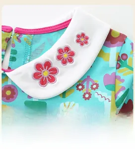 Détail de robe turquoise pour enfant avec col Claudine blanc et broderie florale rose