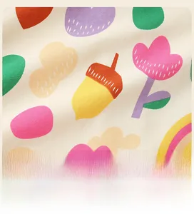 Gros plan sur un tissu en coton doux avec des motifs colorés de glands, fleurs et arcs-en-ciel