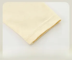 Gros plan des poignets côtelés du t-shirt jaune montrant les détails de couture