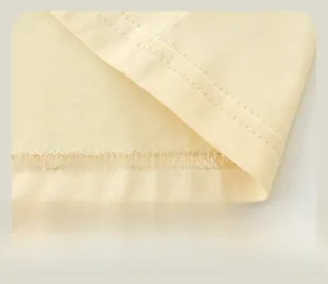 Gros plan sur les coutures doubles et la finition de l'ourlet d'un haut en tricot beige