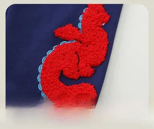 Detail of 3D dinosaur chenille embroidery on navy blue knitted toddler trousers