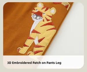 Detail of 3D tiger patch embroidery on orange cotton toddler joggers for boys