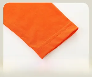 Gros plan des poignets en tricot de coton orange avec détails de couture à double aiguille