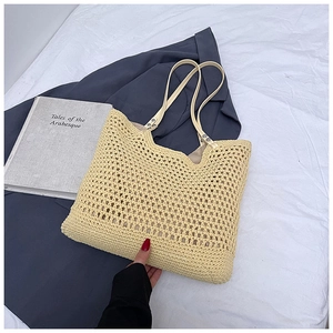 Detail of yellow hollow-out woven tote bag with leather handles on soft fabric backdrop