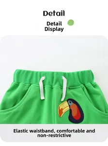 Detail of green kids shorts with elastic waistband and colorful toucan bird embroidery