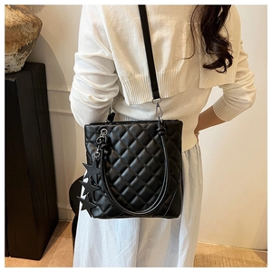 Détail du sac seau noir matelassé avec étoiles porté par un mannequin en tenue chic