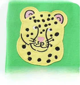 Close-up of a cartoon leopard embroidered patch on green knitted fabric for boys' shorts