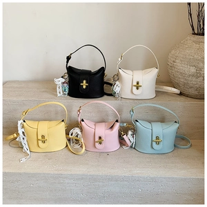 Collection of textured leather bucket bags with pearl charms on stone steps in five colors