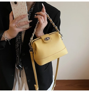 Detail of bright yellow litchi leather bucket bag with silver chain handle and metal clasp