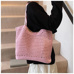 Detailed shot of pink crochet tote bag with leather strap worn by a model in interior