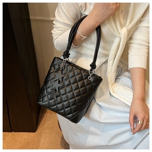 Détail du sac seau noir matelassé avec breloques étoiles et poignée en cuir ronde
