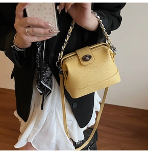 Detail view of yellow lychee grain leather handbag with silver chain and metal twist lock