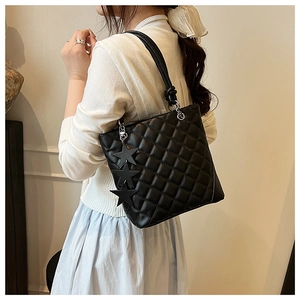 Détail du sac seau matelassé noir avec breloques étoiles et anneaux métalliques