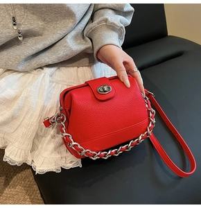 Detail of red lychee leather handbag featuring silver twist lock and chain strap