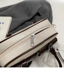 Close-up of smooth silver metal zipper and brown leather trim on a Boston bag