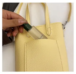 Détail de la poche arrière d'un sac en cuir litchi jaune avec un petit flacon pulvérisateur