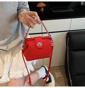 Detail of red pebbled leather doctor bag with silver chain handle and metal twist lock