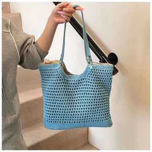 Detail view of light blue crocheted tote bag featuring hollow mesh and faux leather straps