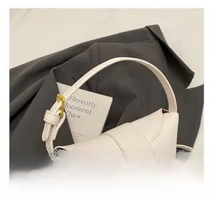 Detail of white lychee leather handbag featuring a golden twist lock on a grey suit